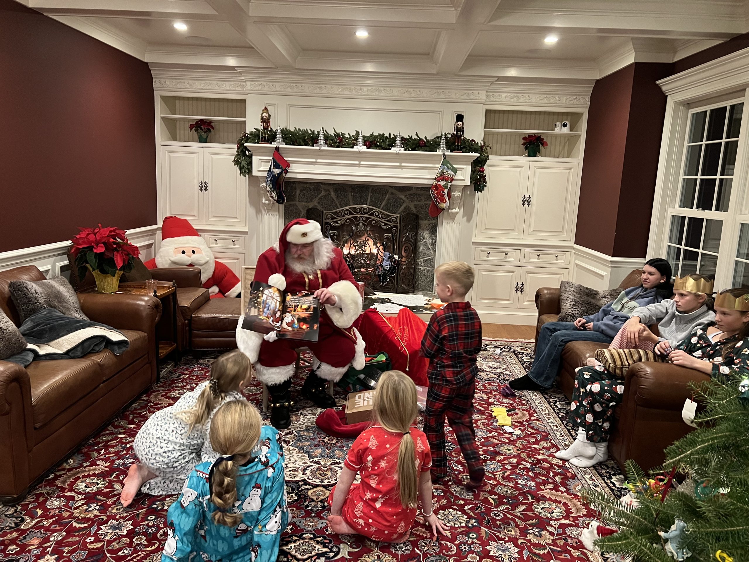 Santa Claus Rose sharing a picture book with children gathered around him beside a fireplace